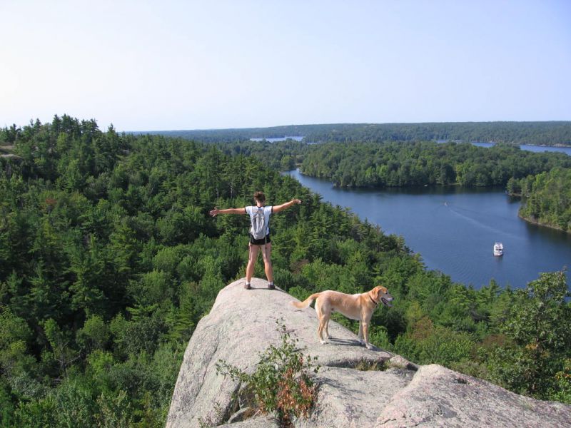 Woman and dog atop Rock Dunder looking out over the treetops